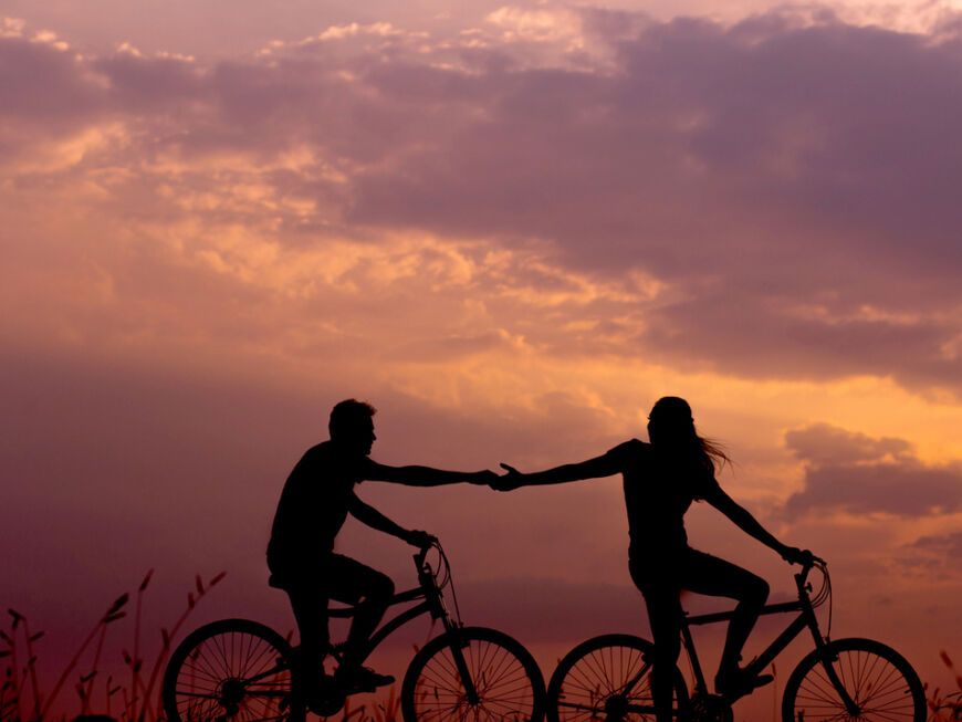 verliebtes Paar auf Fahrrädern hält Händchen
