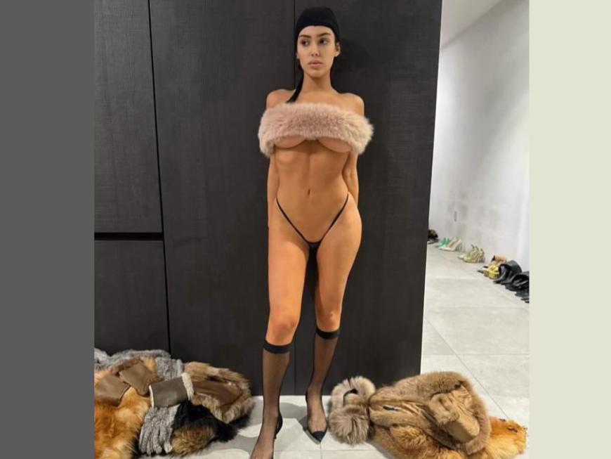 Bianca Censori steht leicht bekleidet vor einem Kleiderschrank