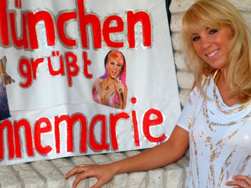 "Zicke"-Annemarie vor einem Plakat mit der Aufschrift "München grüßt Annemarie" im Haus ihrer Eltern in Dessau-Roßlau