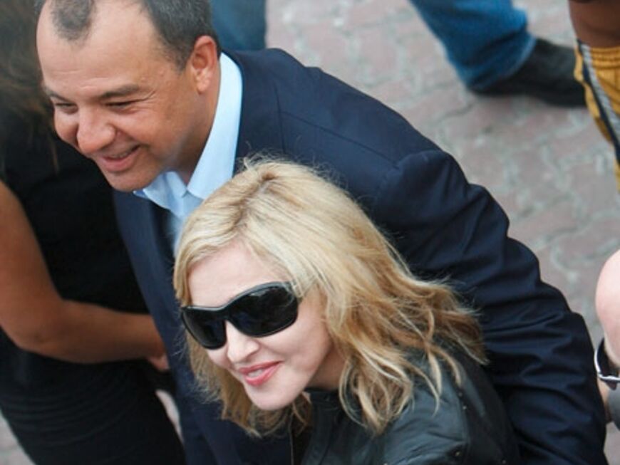 Madonna wird von Rios Gouverneur, Sergio Cabral, umarmt und durch die Viertel geführt
