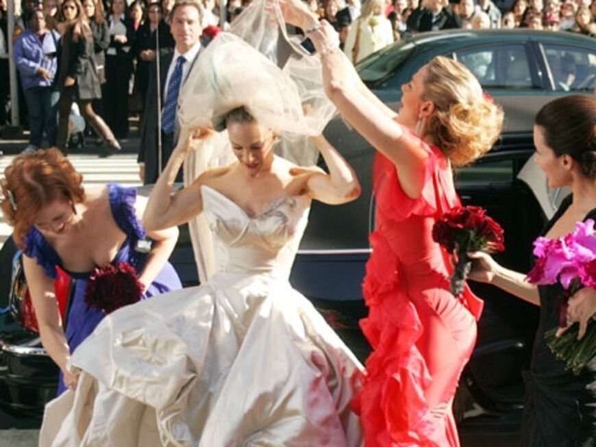 Beim Aussteigen aus der schwarzen Limousine zupfen Miranda, Charlotte und Samantha Carries Hochzeitskleid von Vivienne Westwood zurecht. Doch dann geschieht das Unfassbare: