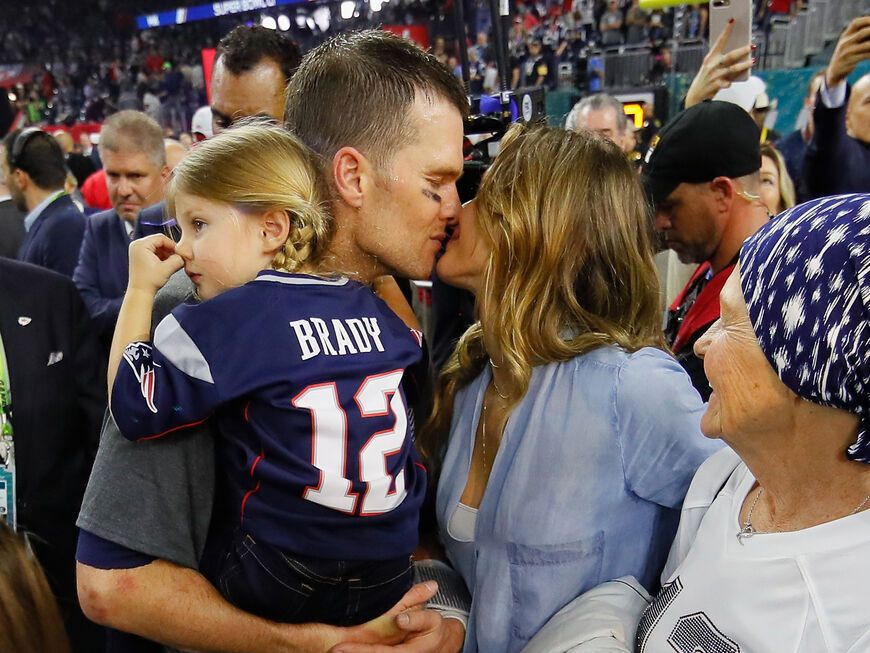Tom Brady küsst Gisele Bündchen, er hat ihre gemeinsame Tochter auf dem Arm