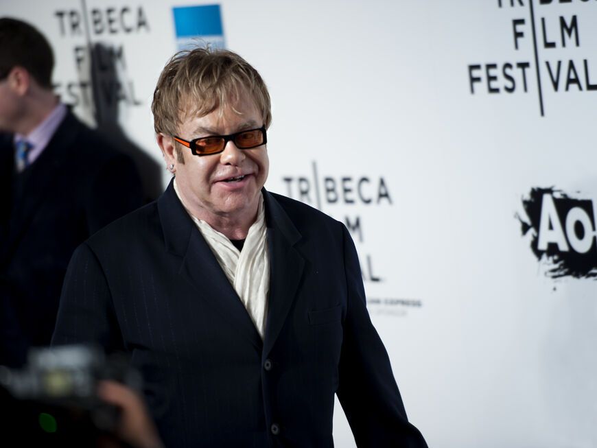 Elton John vor einer weißen Wand