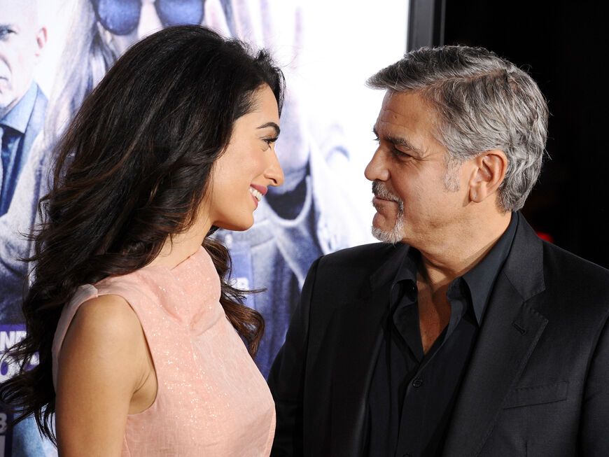 George Clooney und Amal Clooney schauen sich liebevoll an.