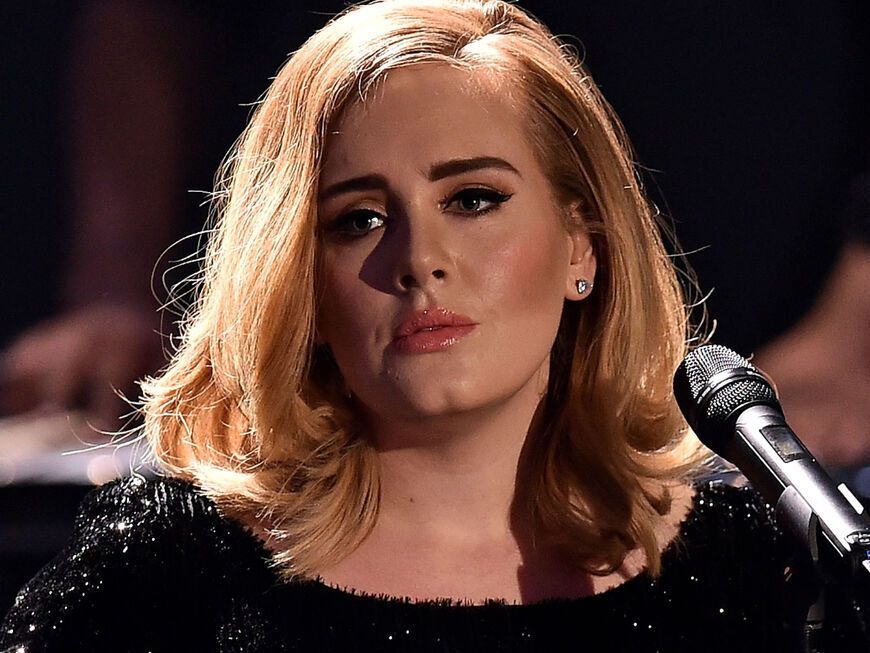 Adele guckt traurig mit Mikrofon.