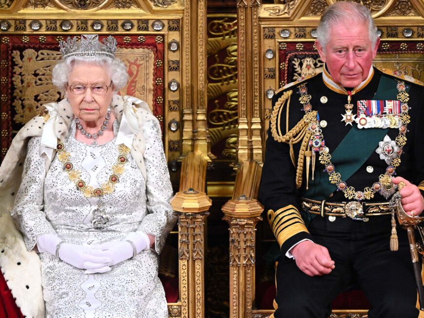 Prinz Charles und Queen nebeneinander auf zwei Thronen