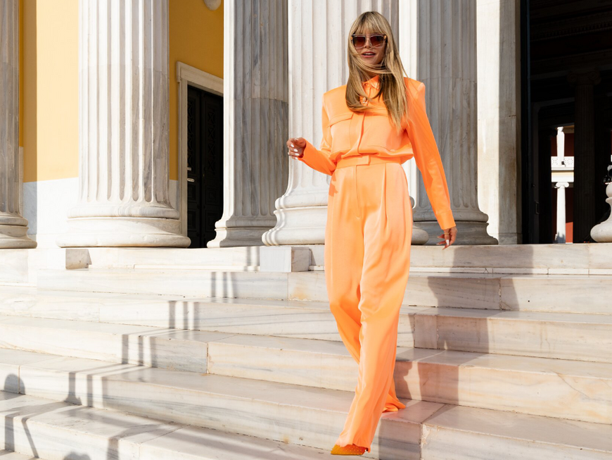Heidi Klum in orangenem Outfit für Staffel 17 von GNTM