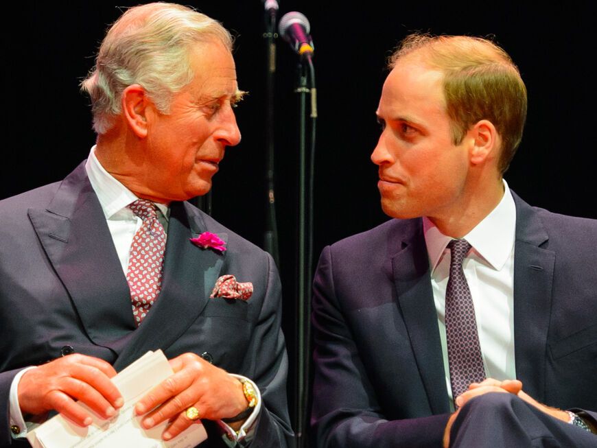 König Charles und Prinz William sitzen lächeln nebeneinander