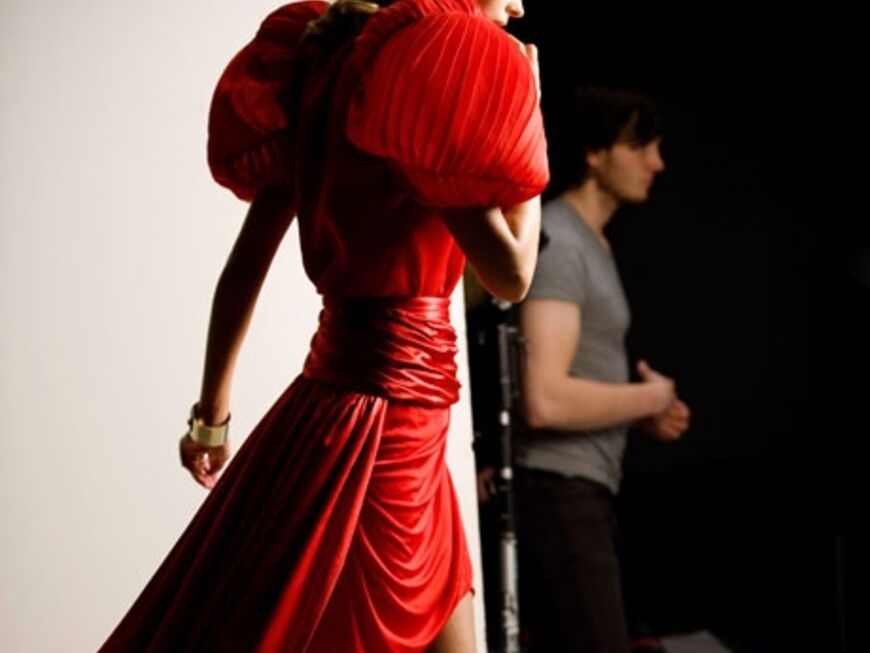 Julia Stegner lächelt in einem roten Seidenkleid von Anne Valérie Hash.