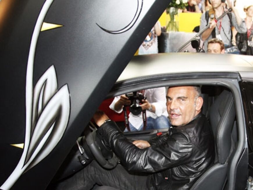 Audigier sitzt in einem Lamborghini, der auf dem Stand seines Labels "Ed Hardy" steht