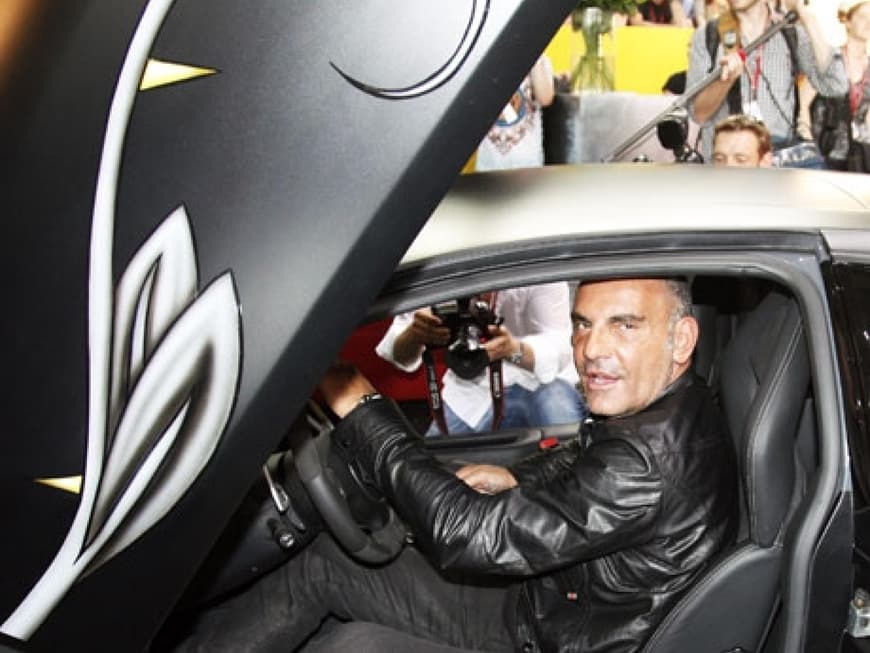 Audigier sitzt in einem Lamborghini, der auf dem Stand seines Labels "Ed Hardy" steht