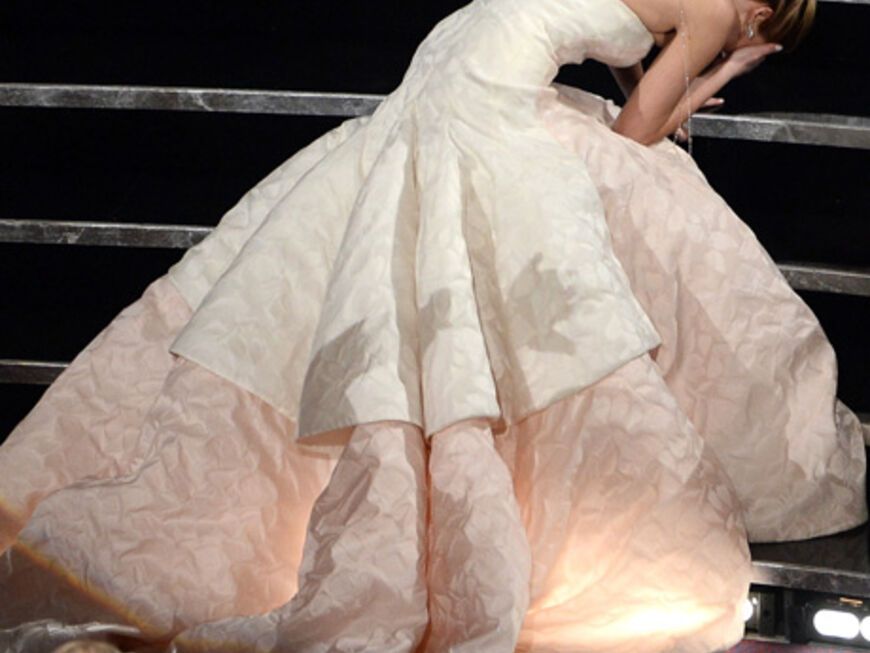 Vor Aufregung fällt sie auf dem Weg zur Bühne auf den Treppen über ihr Kleid