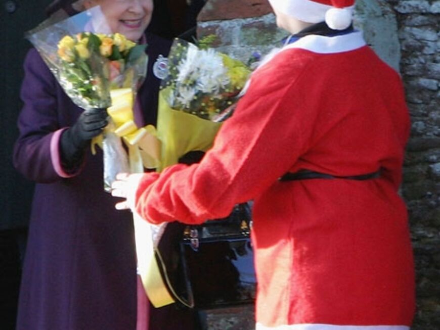 Queen Elisabeth II bekommt von einem verkleideten Santa Claus Blumen überreicht