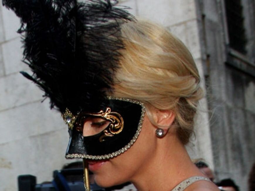Schauspielerin Charlize Theron hält sich eine Maske vors Gesicht - als Anspielung auf die venezianische Tradition der Maskenbälle