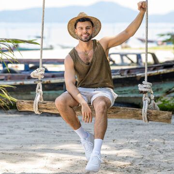 "Charming Boys"-Kandidat Martin Angelo lacht auf einer Schaukel am Strand