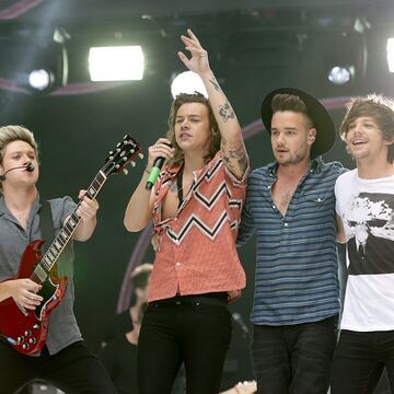 One Direction singen auf der Bühne, Niall Horan hält eine Gitarre in der Hand, Harry Styles ein Mikro
