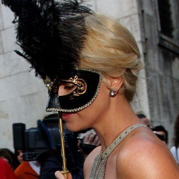 Schauspielerin Charlize Theron hält sich eine Maske vors Gesicht - als Anspielung auf die venezianische Tradition der Maskenbälle