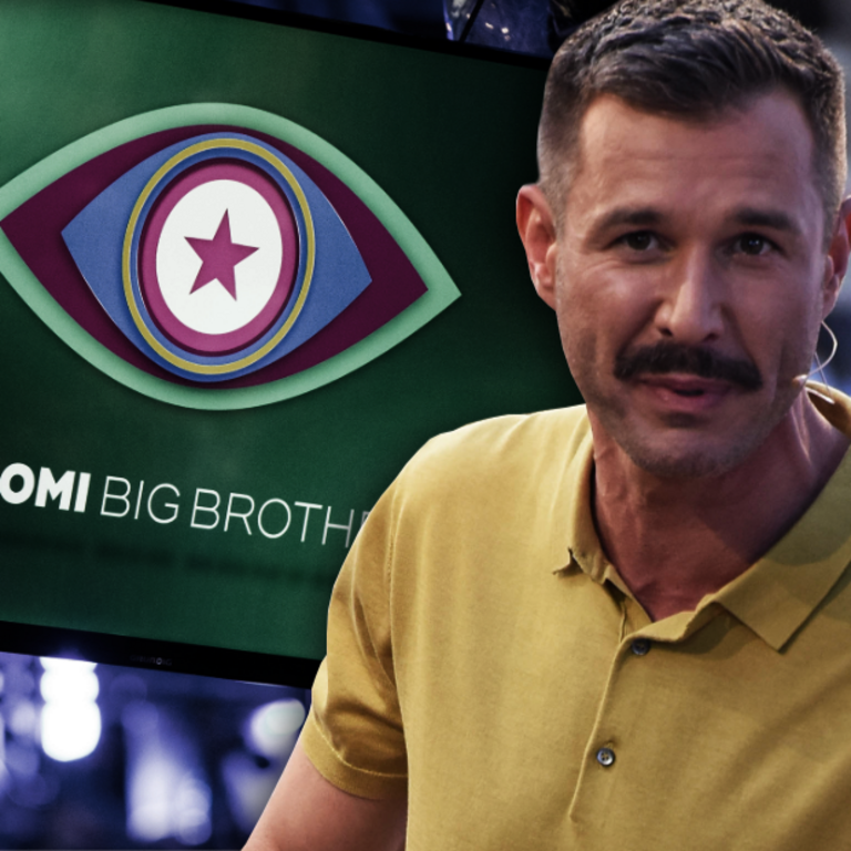 Jochen Schropp steht vor einem Promi Big Brother-Bildschirm.