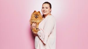 Sarafina Wollny mit Hund Feivel auf dem Arm vor einer pinken Wand