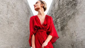 Frau im roten Seidenkleid vor Steinwand