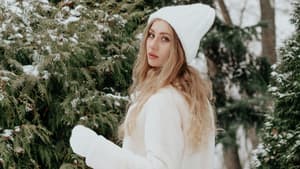 Frau mit weißem Winter-Look vor verschneiten Tannen