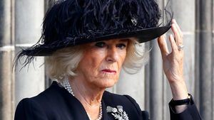 Queen Consort Camilla blickt ernst und fasst sich an den Hut