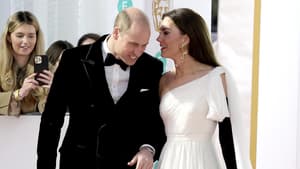 Prinzessin Kate flüstert Prinz William auf dem Roten-Teppich etwas zu. 