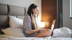 Frau sitzt im Bett am Laptop