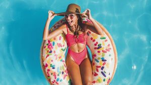 Frau im Badeanzug schwimmt auf Donut