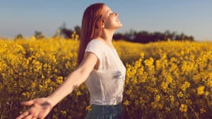 Frau mit ausgebreiteten Armen in Blumenwiese