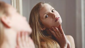 Teenager Mädchen guckt Haut vor dem Spiegel an