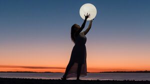 Frau hält Mond in den Händen