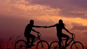 verliebtes Paar auf Fahrrädern hält Händchen