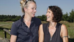Ulrike Folkerts und Partnerin Katharina Schnitzler sehen sich an und lachen.