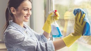 Frau putzt Fenster mit Lappen und Sprühflasche