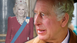 König Charles besorgt - im Hintergrund Königin Camilla lächelnd