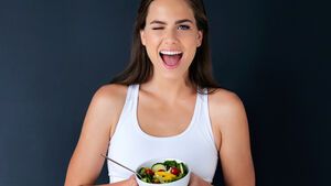 schlanke Frau hält veganen Salat vor sich