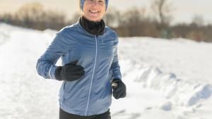 Frau joggt lächelnd im Schnee
