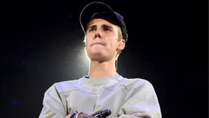 Justin Bieber steht mit verschränkten Armen und zusammengepressten Lippen da.