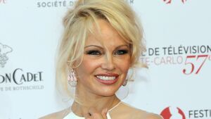 Pamela Anderson lächelt im weißen Kleid.