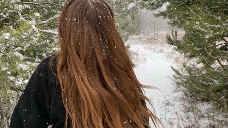 Frau mit langen Haaren geht im verschneiten Wals spazieren