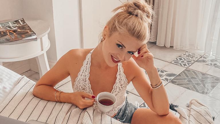 Frau mit strahlender Haut trinkt Kaffee am Bett