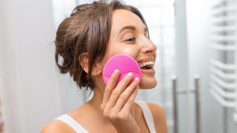 Frau reinigt Gesichts mit Silikonbürste