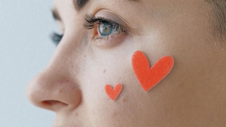 Frau mit Herz-Stickern im Gesicht