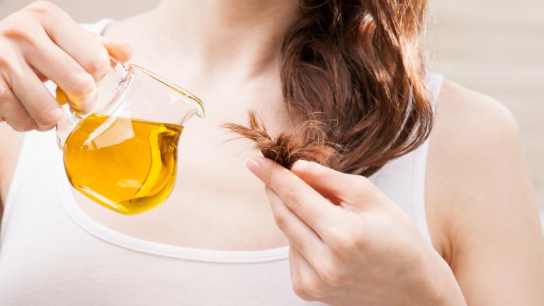 Frau pflegt trockene Haarspitzen mit Olivenöl