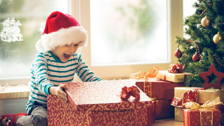 Kind öffnet Weihnachtsgeschenk und freut sich