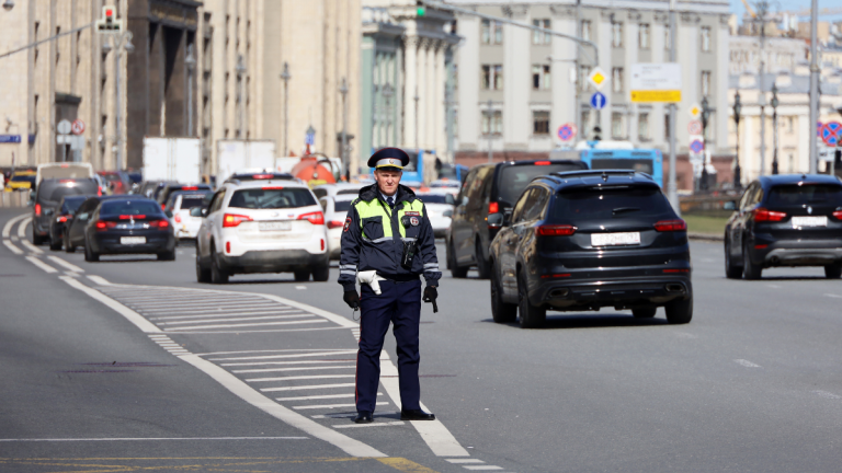 Polizist steht auf der Straße hinter fahrenden Autos